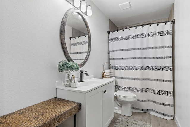 bathroom with visible vents, toilet, vanity, wood finished floors, and a shower with curtain