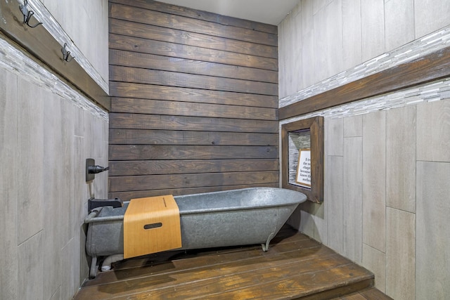 interior space featuring hardwood / wood-style floors, a soaking tub, and wooden walls