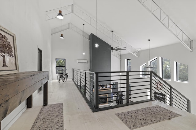 hallway featuring a wall unit AC, tile patterned floors, high vaulted ceiling, and an upstairs landing