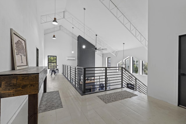 hall with high vaulted ceiling, a wealth of natural light, and an upstairs landing