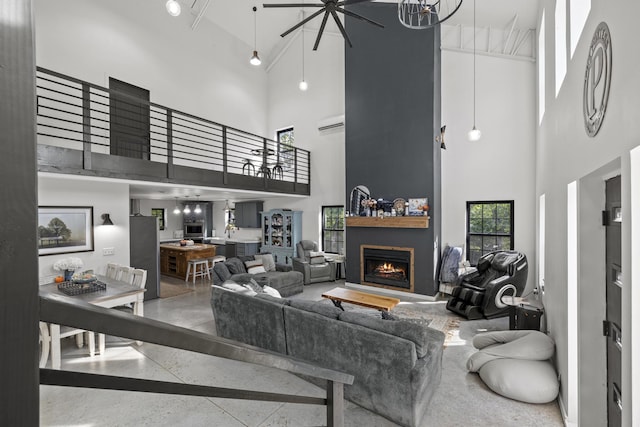 living room featuring a warm lit fireplace, a high ceiling, speckled floor, and a wall mounted AC