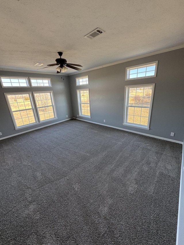 spare room featuring visible vents, dark carpet, ornamental molding, a textured ceiling, and baseboards