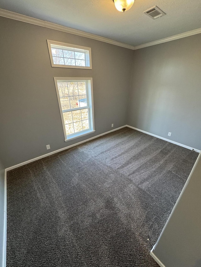 spare room with dark colored carpet, visible vents, ornamental molding, a textured ceiling, and baseboards