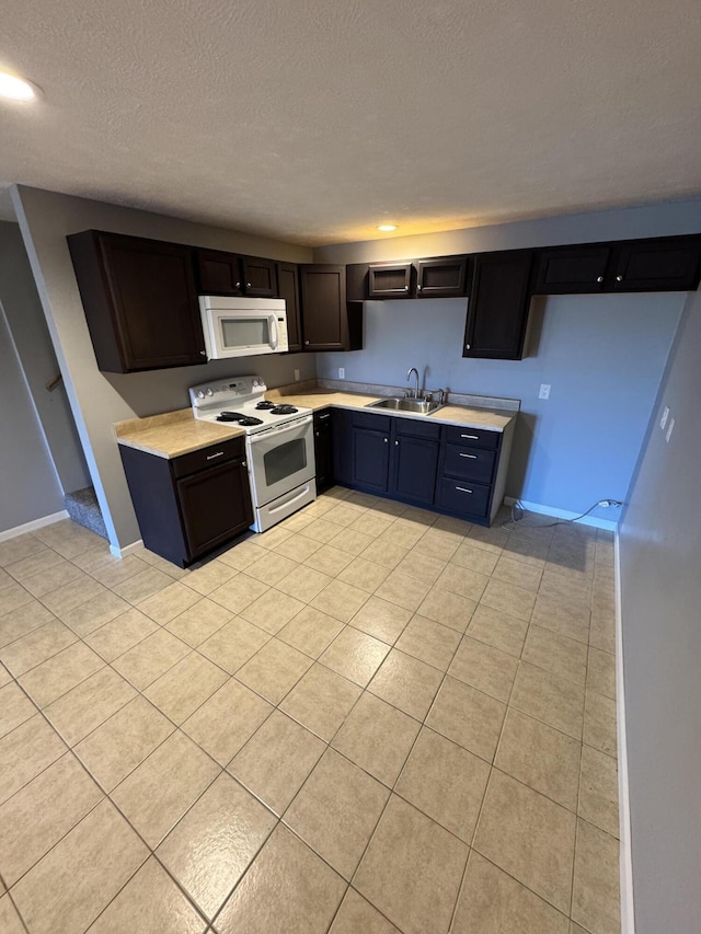 kitchen with light countertops, white appliances, a sink, and baseboards