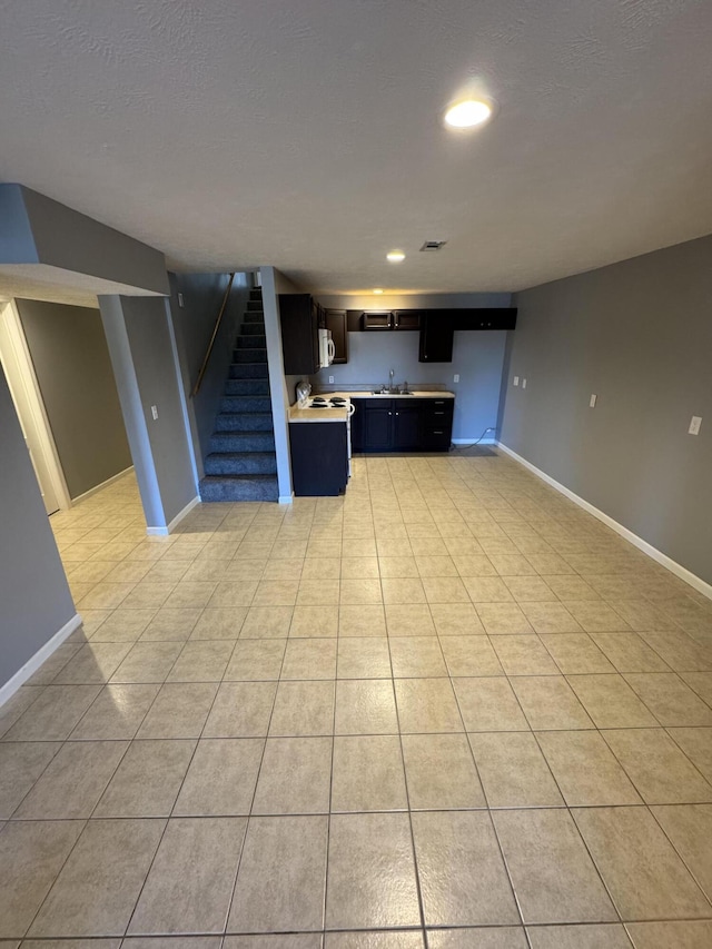 kitchen featuring light tile patterned flooring, baseboards, light countertops, and open floor plan