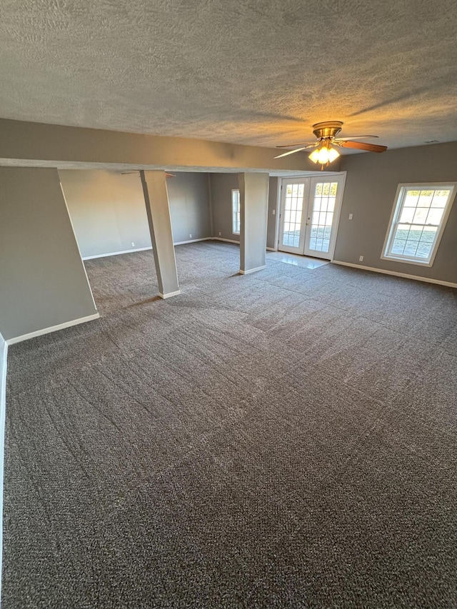 empty room featuring a textured ceiling, french doors, carpet, and baseboards