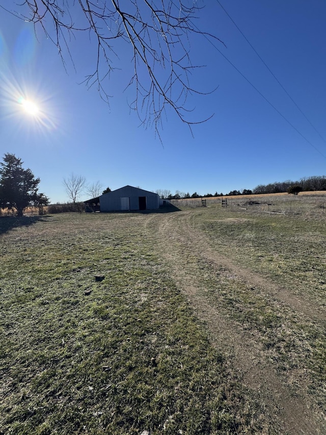 view of yard with a pole building, a rural view, and an outdoor structure