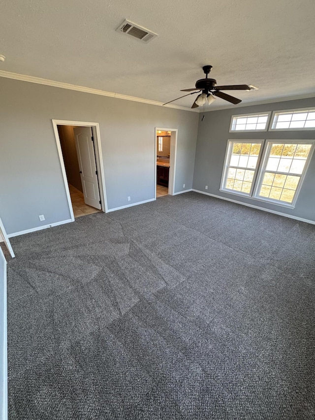 unfurnished room with carpet floors, crown molding, visible vents, and a textured ceiling