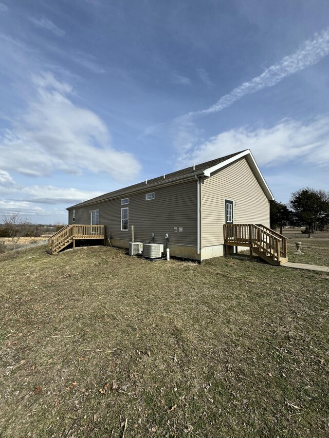 back of property with central air condition unit, a deck, and a lawn