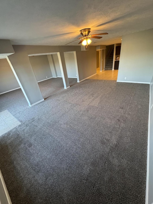 unfurnished room with carpet, stairway, a ceiling fan, a textured ceiling, and baseboards