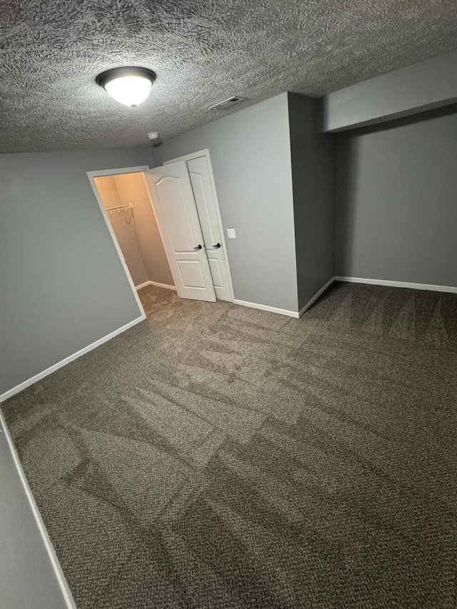 interior space featuring carpet floors, a textured ceiling, and baseboards