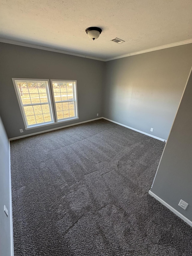 empty room with a textured ceiling, dark colored carpet, baseboards, and crown molding