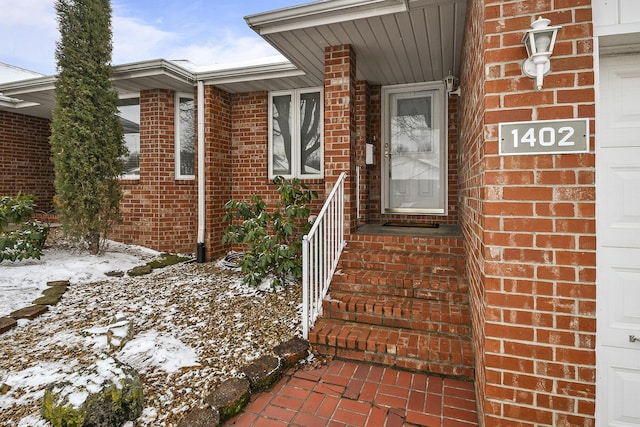 entrance to property with a garage and brick siding