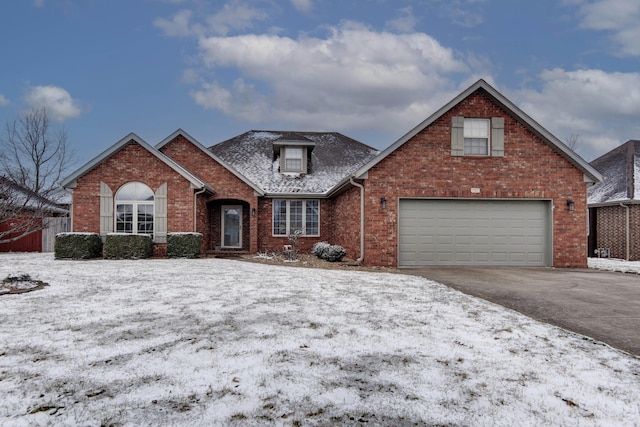 traditional-style house featuring a garage, brick siding, driveway, and fence