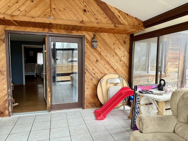 interior space with wood walls, lofted ceiling with beams, and tile patterned floors