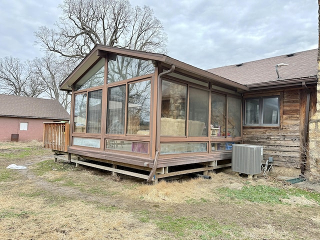 back of house with roof with shingles, cooling unit, and a sunroom