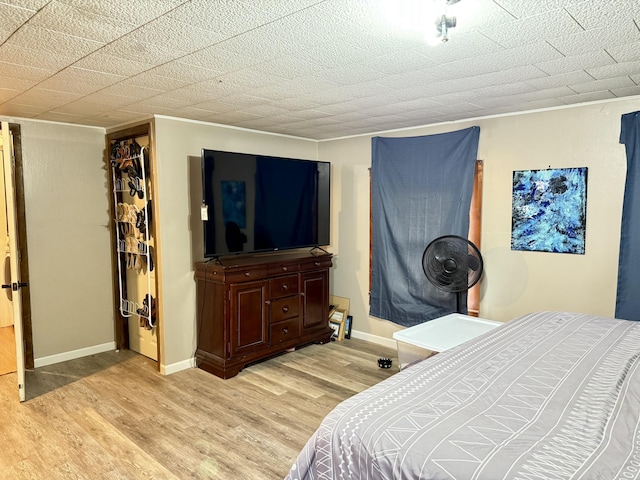 bedroom featuring ornamental molding, light wood-type flooring, and baseboards