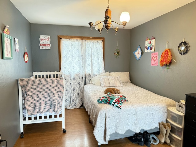 bedroom featuring an inviting chandelier and wood finished floors