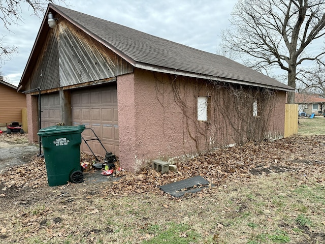 view of property exterior featuring a garage, an outdoor structure, and a shingled roof