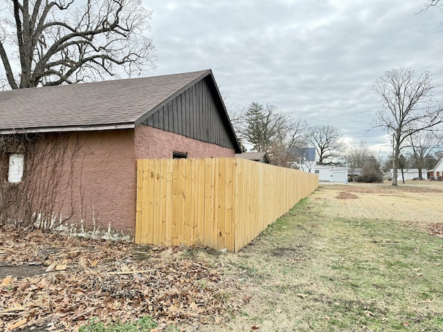 exterior space featuring a shingled roof, fence, and stucco siding