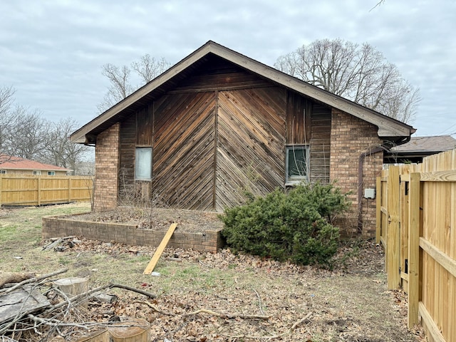 view of property exterior featuring brick siding and fence