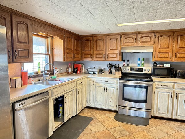 kitchen featuring a toaster, light countertops, appliances with stainless steel finishes, a sink, and under cabinet range hood