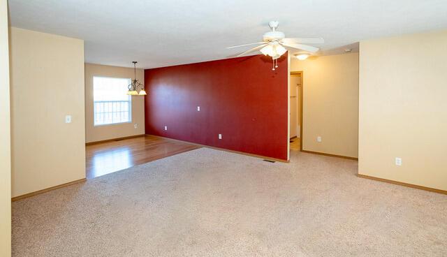 carpeted spare room with a ceiling fan and baseboards