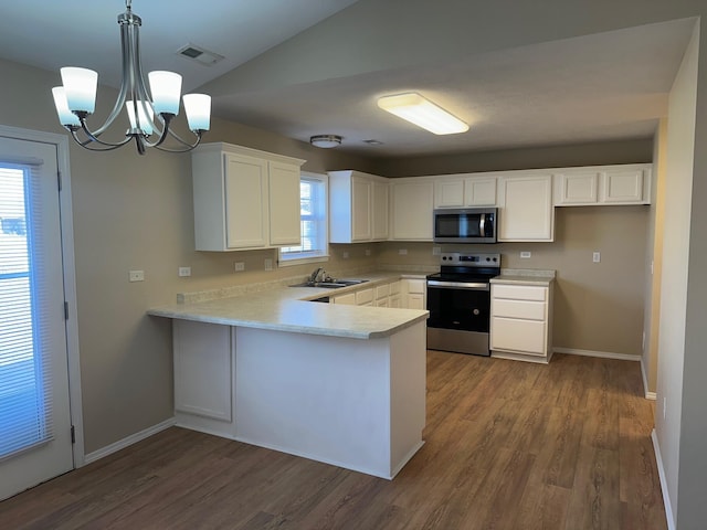 kitchen featuring stainless steel appliances, a sink, a peninsula, and wood finished floors