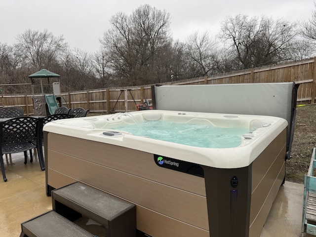 view of patio / terrace with fence and a hot tub