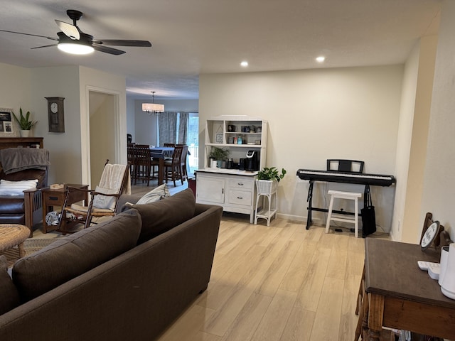 living area featuring light wood finished floors, recessed lighting, and ceiling fan with notable chandelier