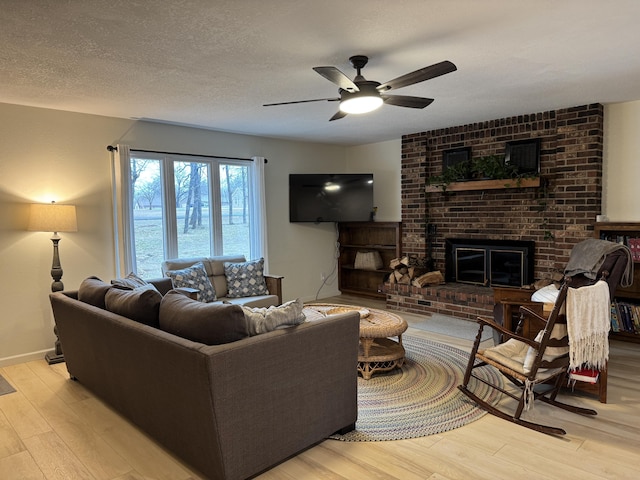 living room featuring a brick fireplace, a textured ceiling, baseboards, and wood finished floors