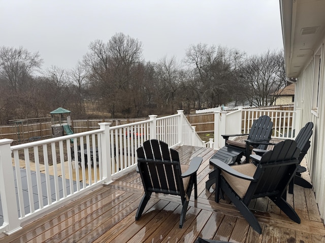 wooden terrace featuring a playground and a fenced backyard