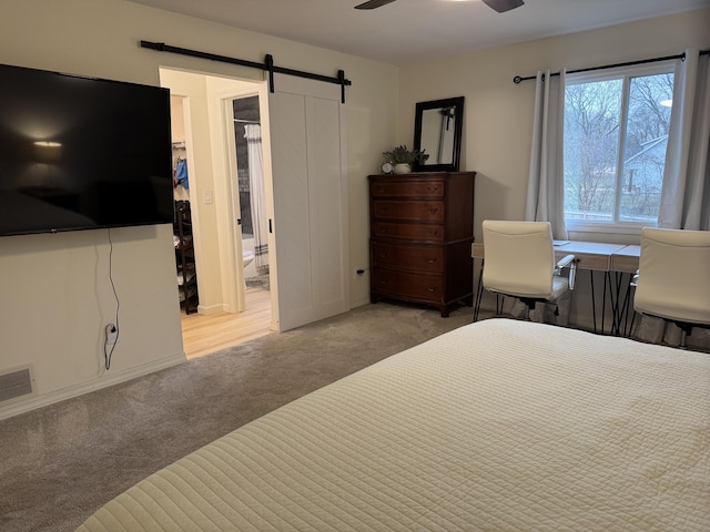 carpeted bedroom with ceiling fan, a barn door, and visible vents