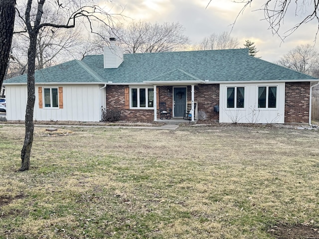 single story home with roof with shingles, a front lawn, board and batten siding, and brick siding