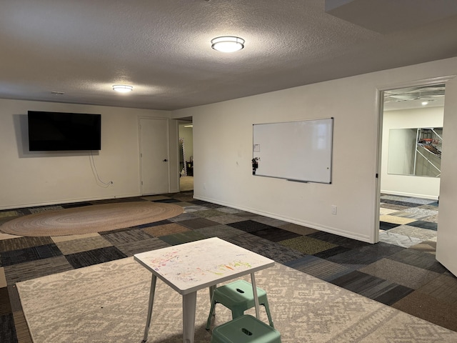 interior space with a textured ceiling, dark carpet, and baseboards