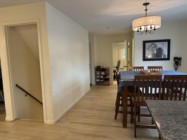 dining room with a chandelier, light wood-style flooring, and baseboards