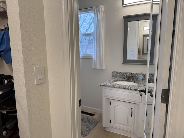 bathroom featuring visible vents, vanity, baseboards, and wood finished floors