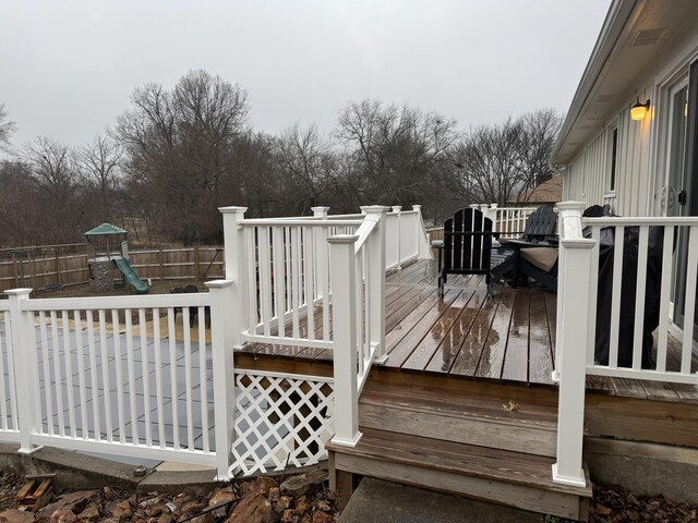 wooden deck with a playground and fence