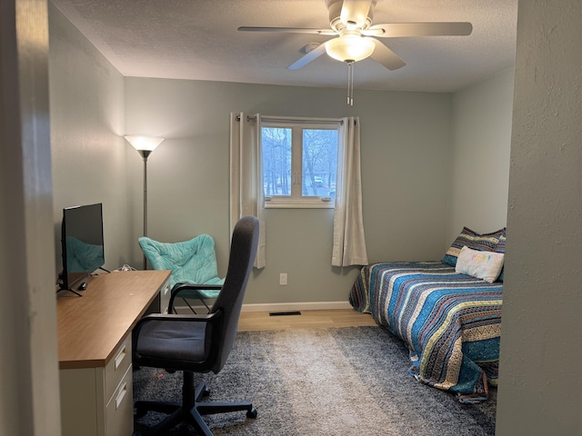 bedroom with a ceiling fan, visible vents, a textured ceiling, and wood finished floors