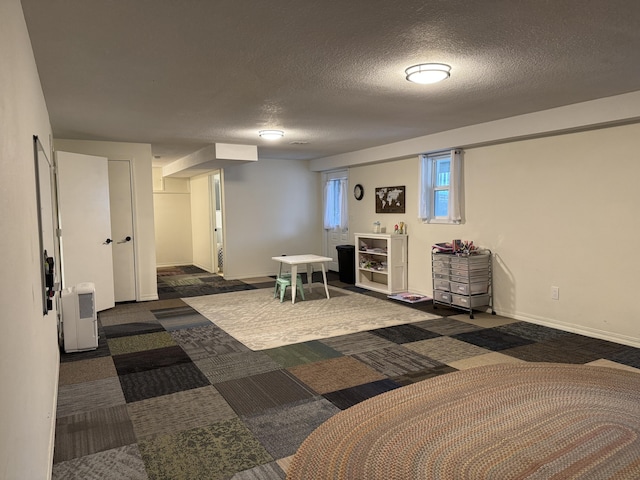 basement featuring dark carpet, a textured ceiling, and baseboards