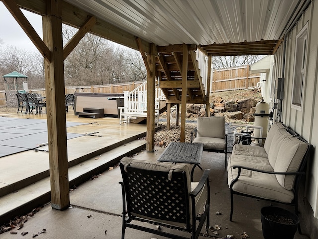 view of patio / terrace with stairway, a fenced backyard, a hot tub, and an outdoor hangout area