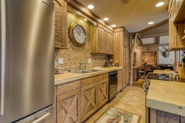 kitchen featuring black dishwasher, tasteful backsplash, light countertops, freestanding refrigerator, and a sink