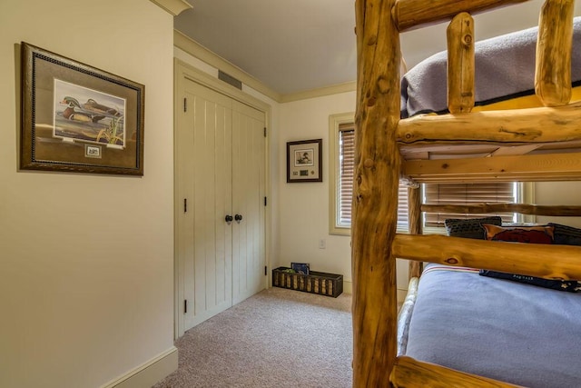 carpeted bedroom with baseboards, a closet, visible vents, and crown molding