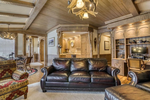 living area with an inviting chandelier, wood ceiling, beam ceiling, and a wainscoted wall