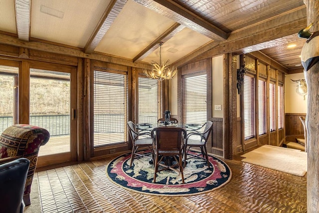 dining space with a chandelier, wainscoting, plenty of natural light, and wooden walls