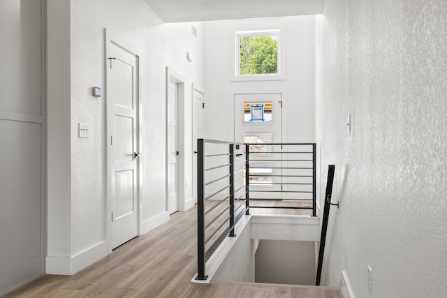 stairway with a high ceiling, baseboards, wood finished floors, and a textured wall