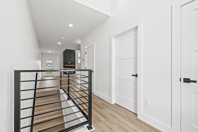 hallway with baseboards, an upstairs landing, light wood-style flooring, and recessed lighting