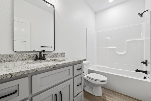 full bathroom with washtub / shower combination, vanity, wood finished floors, and toilet