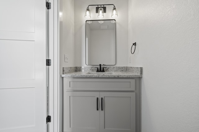 bathroom featuring a textured wall and vanity