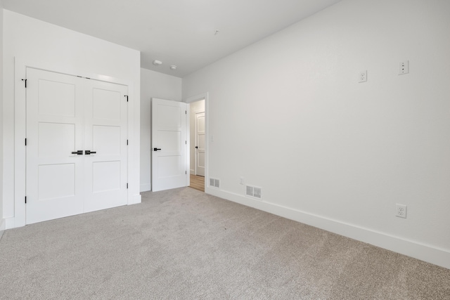 unfurnished bedroom with carpet, a closet, visible vents, and baseboards